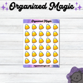 A sheet of planner stickers featuring a grid of yellow, orange, and white candy corn illustrations on a white background with purple header and footer bands. The sheet is displayed on a white wood-plank surface, with the brand name 'Organized Magic' printed at the top of the image and a small purple cat illustration in the bottom right corner.