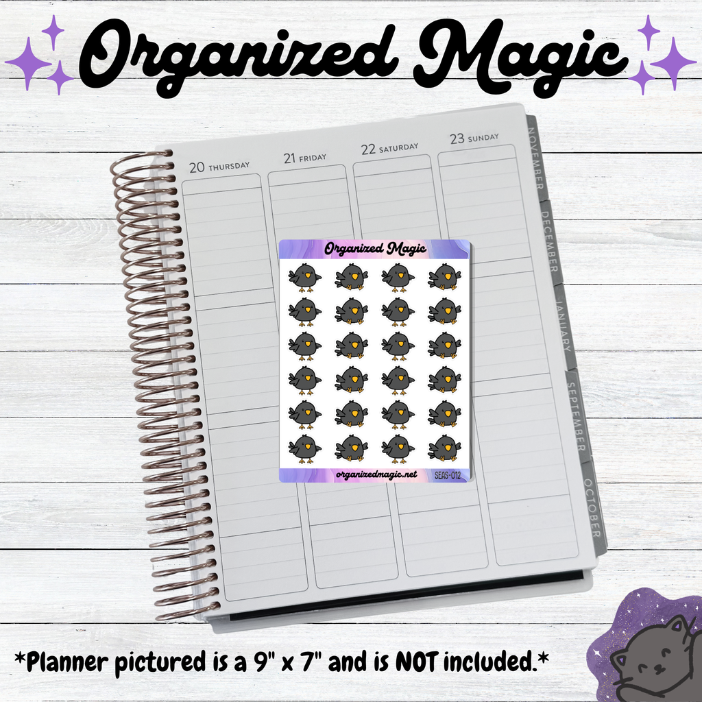A weekly planner page shown open on a whitewashed wood background, with a sheet of matching doodle crow stickers from Organized Magic placed over the center. 