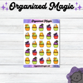 A sheet of Halloween-themed planner stickers featuring colorful cupcakes with pumpkins, ghosts, and witch hats, displayed on a white wood background with 'Organized Magic' branding.