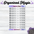 A sheet of small moon phase planner stickers displayed on a white wood background, with decorative text reading 'Organized Magic' at the top and a small cat illustration in the bottom right corner.